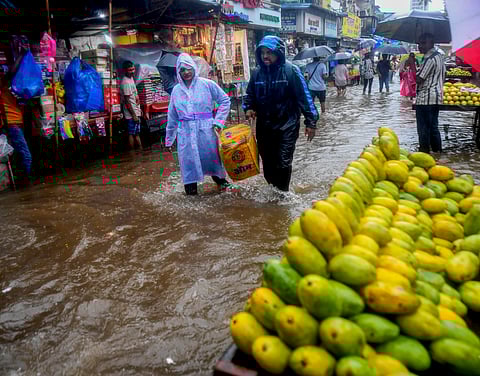 People walk through a waterlogged local market after heavy rainfall outside the Kurla station, in Mumbai, Sunday, July 21, 2024.